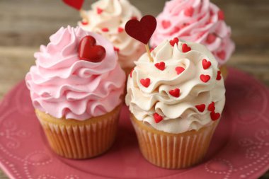 Sevgililer Günün kutlu olsun. Tahta masa üzerinde kalpler şeklinde serpiştirilmiş lezzetli kekler, yakın plan.