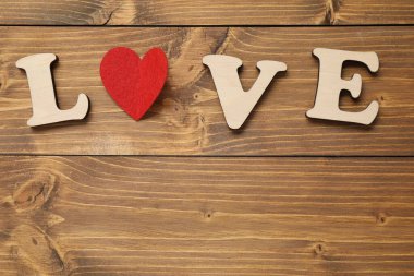 Aşk kelimesi harf ve kırmızı kalpten yapılmıştır. Tahta masada, düz bir şekilde. Metin için boşluk