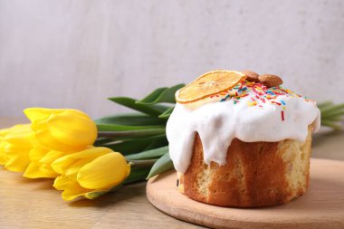 Lezzetli Paskalya pastası ve ahşap masada güzel laleler Gri arka planda, yakın plan