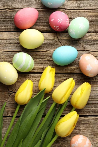 Boyanmış Paskalya yumurtaları ve ahşap masada güzel laleler.