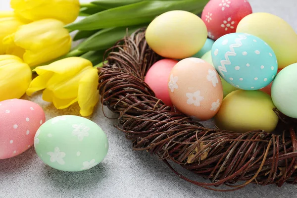 Yuvada boyanmış Paskalya yumurtaları ve gri desenli masada güzel laleler. Yakın plan.