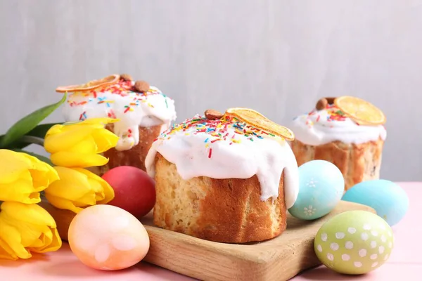 Lezzetli Paskalya pastaları, laleler ve pembe masanın üzerine boyanmış yumurtalar.