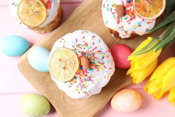 Lezzetli Paskalya pastaları, laleler ve pembe masanın üzerine boyanmış yumurtalar.