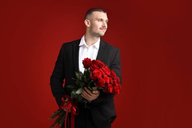 Sevgililer Günü kutlaması. Kırmızı arka planda güzel gül buketi olan adam.
