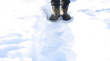 Güneşli karların üzerinde yürüyen adam, yakın plan.