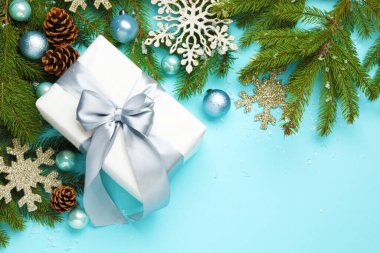 Açık mavi arka planda hediyeli ve dekorlu Noel kompozisyonu, düz. Metin için boşluk