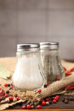 Ahşap masada baharatlı tuzluk ve biberlikler, yakın plan.