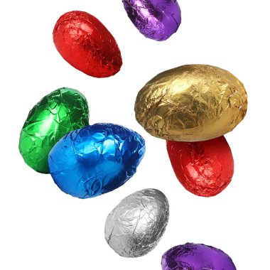 Beyaz arka plana dökülen parlak folyoyla tatlı çikolata yumurtaları