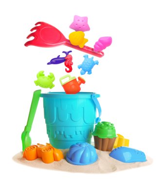 Çocuklar için plaj oyuncakları. Plastik kalıplar ve araçlar beyaz arkaplana karşı kum üzerinde kovaya düşebilir