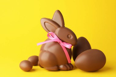 Çikolatalı Paskalya tavşanı ve sarı arka planda yumurtalar.