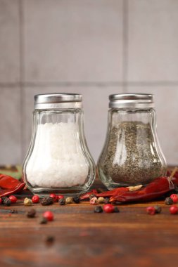 Ahşap masada baharatlı tuzluk ve biberlikler, yakın plan.