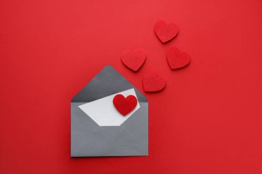 Sevgililer Günün kutlu olsun. Tebrik kartı ve kırmızı arka planda dekoratif kalpler ile zarf düz uzanır