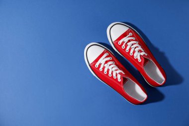 Mavi arka planda bir çift şık spor ayakkabı, üst manzara. Metin için boşluk