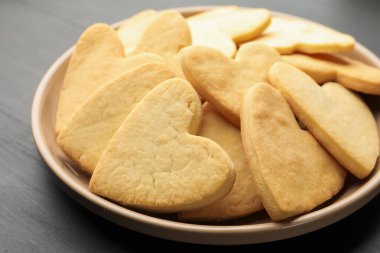 Lezzetli kalp şeklinde tereyağlı kurabiyeler koyu ahşap masada, yakın plan.