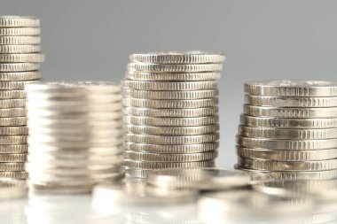 Işık arkaplanına istiflenmiş birçok bozuk para, yakın plan