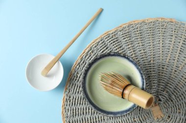 Seramik kasede taze yeşil kibrit, bambu çırpma ve açık mavi masada kepçe, düz uzanma