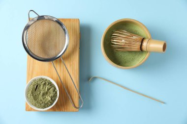 Seramik kasede taze yeşil kibrit, bambu çırpı, kepçe, toz ve süzgeç açık mavi masada düz uzanır