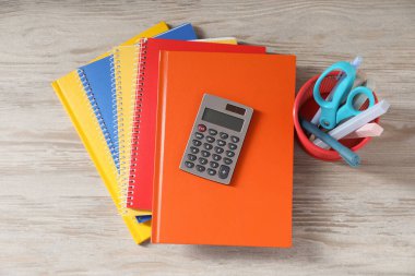 Ev ödevi. Defterler ve farklı kırtasiye malzemeleri açık gri ahşap masa, düz yatak