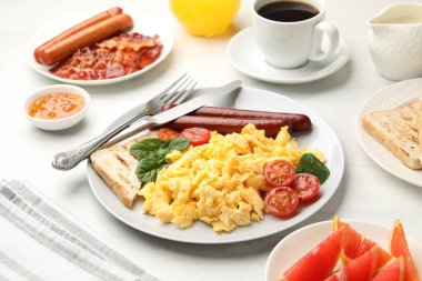 Lezzetli bir kahvaltı. Sosis ve domatesli nefis çırpılmış yumurta. Masada servis ediliyor. Yakın plan.