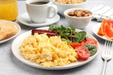 Lezzetli bir kahvaltı. Lezzetli çırpılmış yumurta, sosis ve domatesler gri desenli masa, yakın plan.
