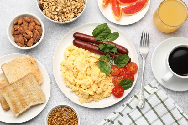 Lezzetli bir kahvaltı. Lezzetli çırpılmış yumurta, sosis ve domatesle servis edilen gri desenli masa, düz.