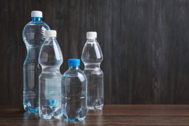 Ahşap masada farklı boyutlarda su şişeleri, metin için yer