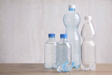 Su şişeleri ahşap masa üzerinde açık gri arkaplan, metin için boşluk