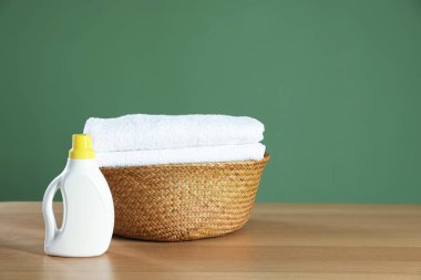 Ahşap masa üzerinde havlular ve deterjan olan çamaşır sepeti koyu yeşil arka plan, metin için boşluk