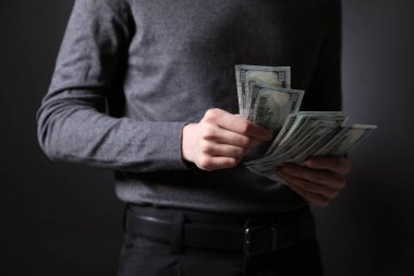 Koyu arka planda dolar banknotları olan iş adamı, yakın plan.