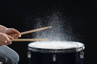 Siyah arkaplanda davul çalan bagetli adam, yakın plan