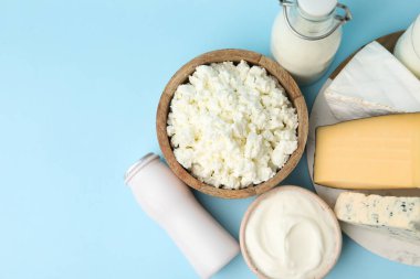 Açık mavi arka planda farklı süt ürünleri, düz yatak. Metin için boşluk
