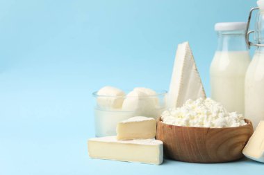 Açık mavi arka planda farklı süt ürünleri, yakın plan. Metin için boşluk