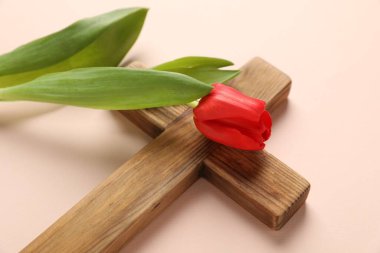 Paskalya özellikleri. Ahşap haç ve bej arka planda güzel lale, yakın plan.