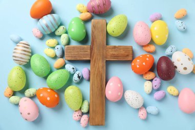 Ahşap haç ve açık mavi arka planda Paskalya yumurtaları, düz yatıyordu.