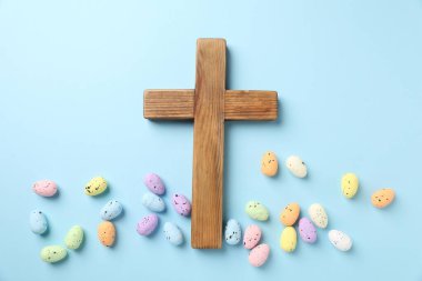 Ahşap haç ve açık mavi arka planda Paskalya yumurtaları, düz yatıyordu.