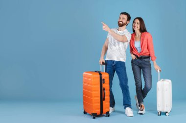 Açık mavi arka planda bavulları olan mutlu çift, mesaj için boşluk