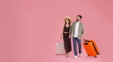 Pembe arka planda bavulları olan mutlu çift, mesaj için yer