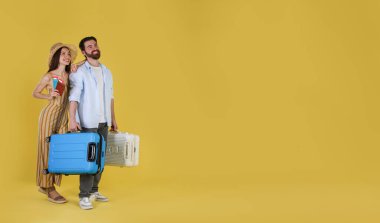 Bavulları, pasaportları ve sarı arka planda biletleri olan mutlu çift, mesaj atmak için yer.