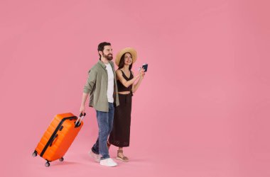 Bavullu mutlu çift, pasaport ve pembe arka planda biletler, mesaj için yer