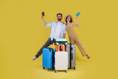 Bavulları, pasaportları ve sarı arka planda biletleri olan mutlu çift.