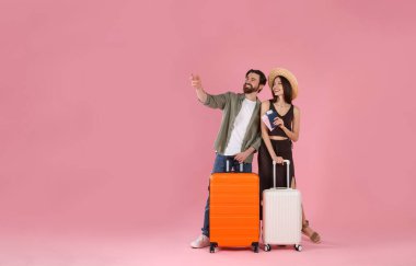 Bavullu mutlu çift, pasaport ve pembe arka planda biletler, mesaj için yer