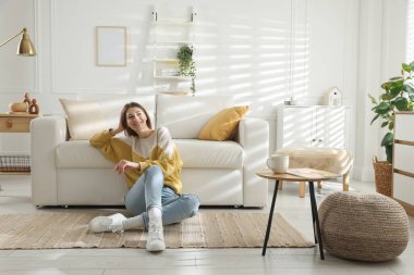 Evdeki koltuğun yanında dinlenen bir kadın.