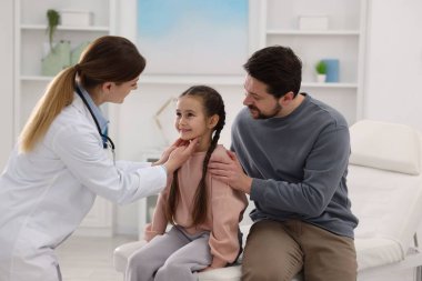 Küçük kız ve babasının hastanede çocuk doktoruyla randevusu var. Çocuğu muayene eden doktor.