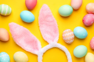 Mutlu Paskalyalar. Sevimli tavşan kulakları ve sarı arka planda boyanmış yumurtalar.