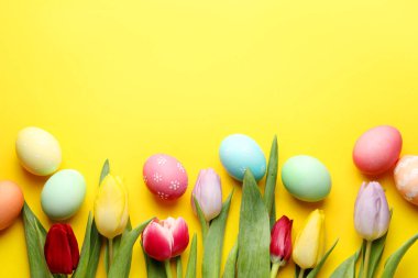 Boyalı Paskalya yumurtaları ve sarı arka planda güzel laleler. Metin için boşluk