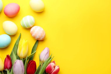 Boyalı Paskalya yumurtaları ve sarı arka planda güzel laleler. Metin için boşluk