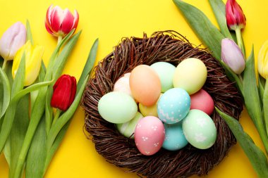 Boyalı Paskalya yumurtaları ve sarı arka planda güzel laleler.