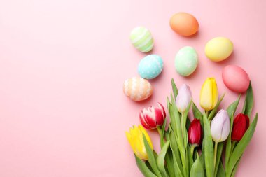Boyalı Paskalya yumurtaları ve pembe arka planda güzel laleler. Metin için boşluk