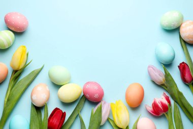 Boyanmış Paskalya yumurtaları ve açık mavi arka planda güzel laleler. Metin için boşluk
