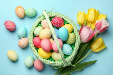 Açık mavi arka planda boyanmış yumurtaları olan Paskalya sepeti düz uzanıyordu.